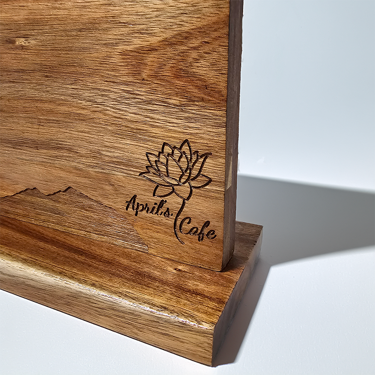 Wooden cutting board with engraved logo and text on a white background